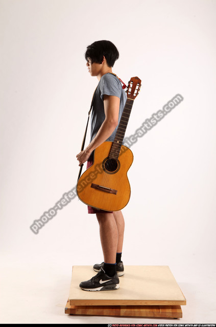 Fifteen Years Old Guitarist With A Black Electric Guitar. Teenage Musician  Holds Guitar, Posing At Studio. The Young Caucasian Guy With A Guitar.  Stylish Musician. Heavy Metal Player. Stock Photo, Picture and